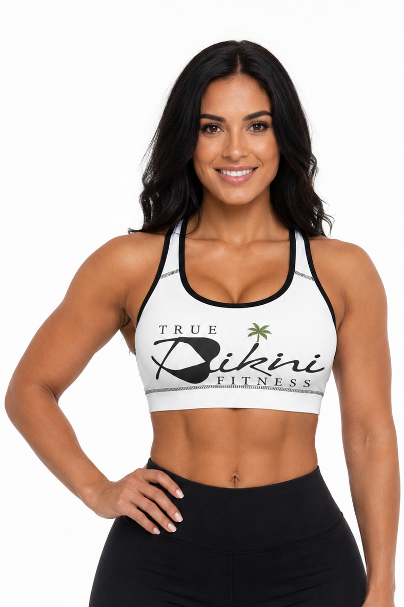 Woman wearing a white sports bra with 'True Bikini Fitness' logo and black leggings on a white background